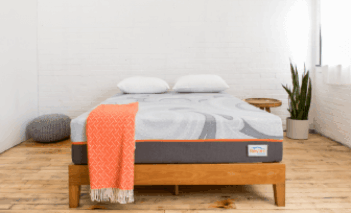 A mattress on bed with an orange throw blanket