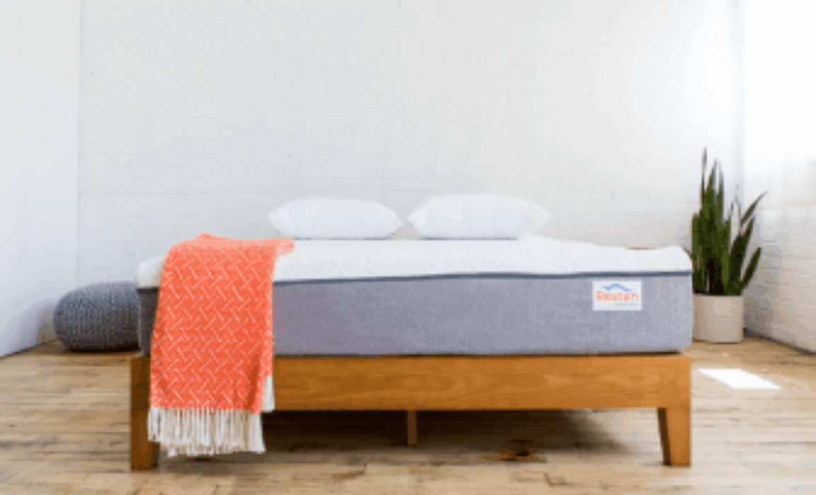 A mattress on bed with an orange throw blanket